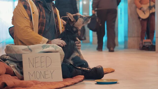 A beggar with a dog are sitting in the underpass