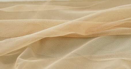 Beige fine mesh close-up. Sewing a wedding dress. Light veil nylon. Handmade tailoring, professional clothing concept. Abstract background. 