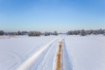 Fototapeta na wymiar ground road among wide snowbound plain, winter outdoor background