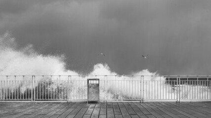 stormy waves crashing against railings against the gray stormy sky