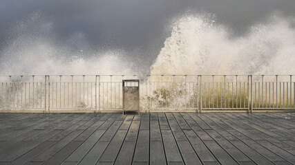 stormy waves crashing against railings against the gray stormy sky