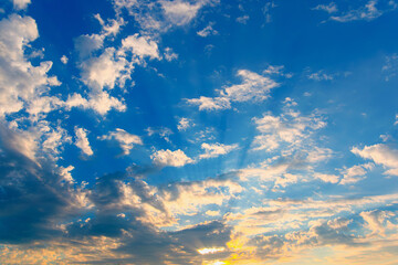 Dramatic sky with feather clouds. Sun's rays shine through clouds. Colorful background.
