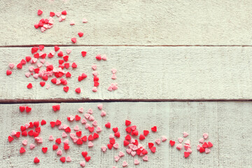 Valentine day background, many small red pink hearts on white wooden table