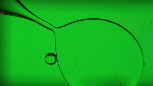 Oil bubbles, streaks on water in light green light, macroscopic