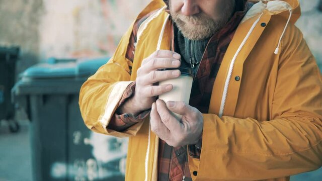 Carton coffee cup in the hands of a homeless man