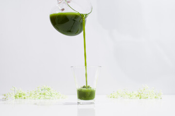 Verter té verde matcha saludable en una taza de vidrio sobre una mesa blanca