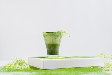 Un vaso de té  matcha con leche decorado con flores y polvo de té verde espolvoreado sobre una...