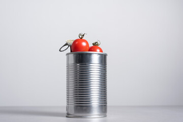 Tomates cherry enteros dentro de una lata de conservas sobre fondo gris	
