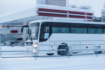 Tourist bus moves in winter along a snow-covered street