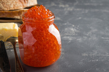 salmon caviar in a glass jar on a gray background close-up