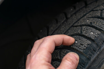 the hand of a person, the driver of the car, touches and checks the condition of the spikes on the...