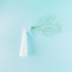 Creative arrangement made of a bottle sprayer and white flowers on a blue background. Minimal spring concept. Spring cleaning and spring time inspiration.