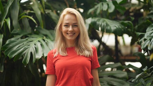 Profile portrait. Closeup of blonde haired beautiful caucasian girl posing before leaves of monstera in tropical forest. Attractive model with healthy skin. Purity, wellness and skincare.