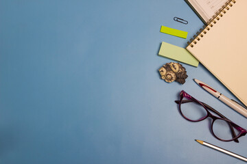 Blue background with stationery and glasses.