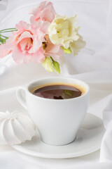 Tranquil coffee moment with blooming soft pink and ivory flowers on a pristine white backdrop, exuding serenity and elegance.