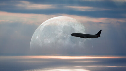 Silhouette of a passenger plane passing in front of the full moon 