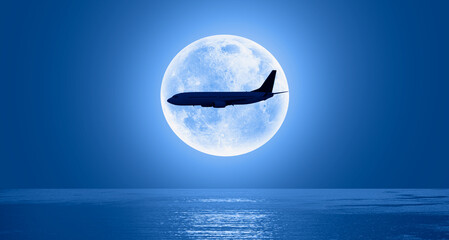 Silhouette of a passenger plane passing in front of the full moon 