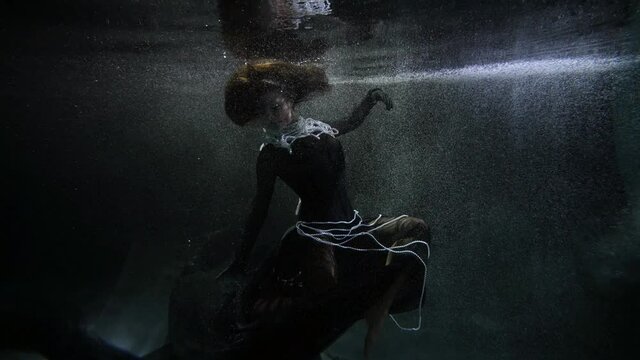 female figure in dark depth of sea or ocean, dramatic and elegant style, floating black dress