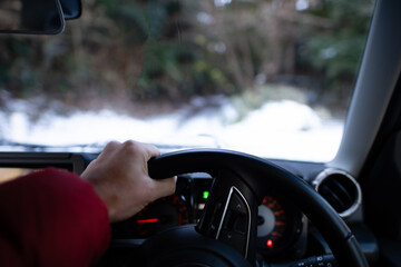 雪道で車を運転する男性の手