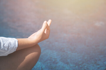 a hand of woman meditating in a yoga pose with blue pool water background. Meditate, relieve stress calm the mind. Nature meditation and spa like zen. relax time concept. copy space for text.