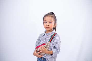 A portrait of a little cute girl in jeans wear, standing and posing with her little chest bag in a studio on white background. 