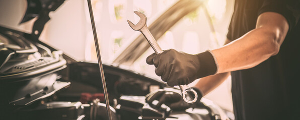 Close-up hand auto mechanic using the wrench to repairing car engine problem. Concepts of check and...