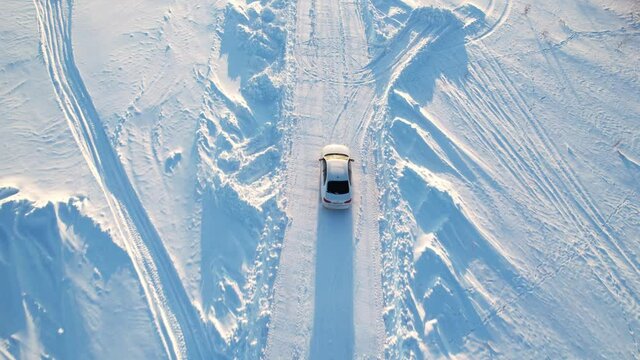 Aerial view. A moving car on a winter road. Following a white car that is driving on a snowy road.