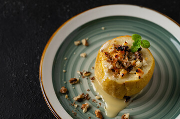 a plate with a healthy dessert, a baked apple with cottage cheese and nuts on a black background