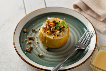 Baked apple with cottage cheese and nuts on a light wooden background