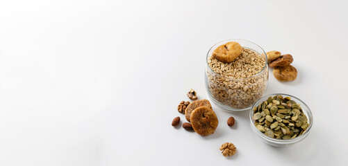Products for a healthy breakfast, rolled oat groats with dried fruits, nuts and pumpkin seeds on a white background, empty space for text, banner