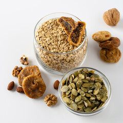 Products for a healthy breakfast, rolled oat groats with dried fruits, nuts and pumpkin seeds on a white background, square format