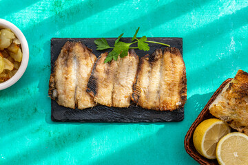 Sardines breaded and fried, on a black slate plate.