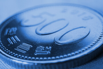 Translation: Bank of Korea. 500 won coin close-up. Blue tinted background or wallpaper on an...