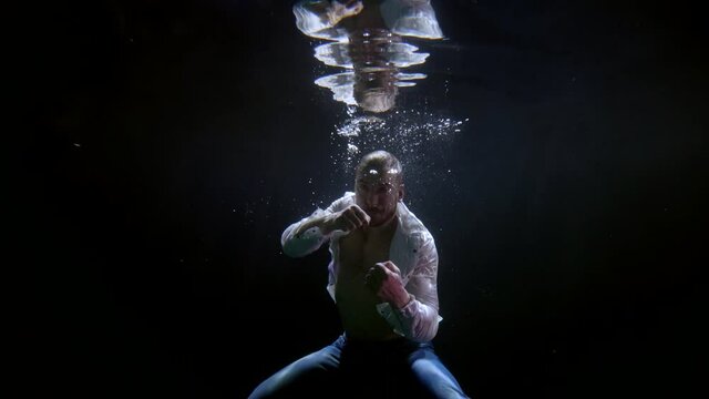 male figure underwater, boxer is fighting, waving fists