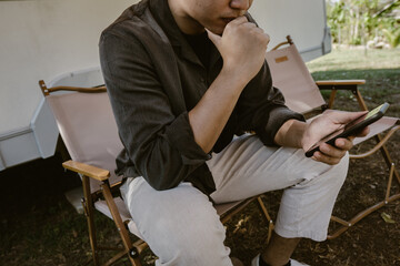 man sitting and using mobile phone with thinking posture, technology and communication concept,dark and moody tone