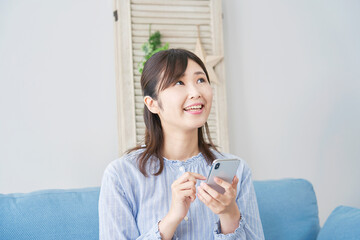 女性　スマホ　リビング　想像する