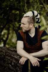 A young man with an interesting depicts a Viking with an ax in an unreliable stylized modern costume