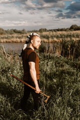 A young man with an interesting depicts a Viking with an ax in an unreliable stylized modern costume