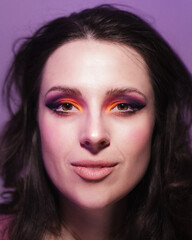 Studio portrait of dark haired woman wearing bright makeup in sunset colours
