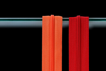 Two zippers, red and orange on a black background