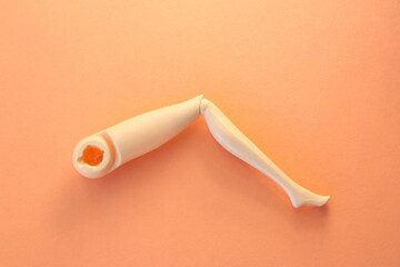 The leg of the plastic doll lies on a pink background.
Close-up of the left leg of the toy doll.