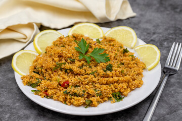 Bulgur salad (kisir) on a dark background. Traditional delicious food. Turkish cuisine appetizers. Horizontal view. close up