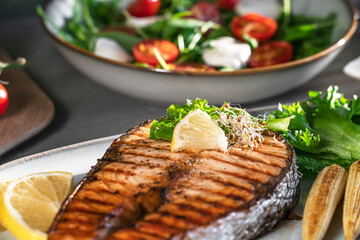 Close-up grilled salmon steak with mini corn, microgreen, salad and lemon. Fried salmon steak and fresh salad and vegetables