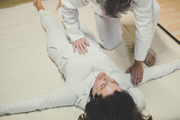 Therapist man doing a Shiatsu massage to a woman. Holistic therapy,  treatment with manipulation by...