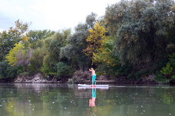 Fototapeta na wymiar Strong and fit woman rowing with SUP stand up paddle board in Danube river at the summer evening