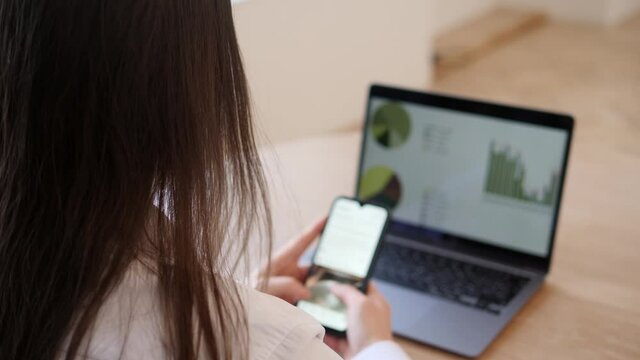 Woman looks at the news feed in the application while working on a laptop in the office.