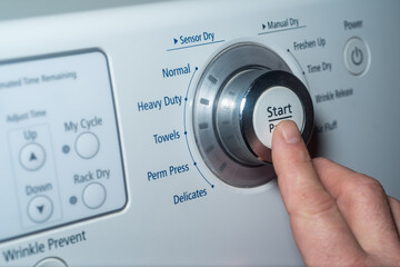 Finger pushing start button on electric dryer