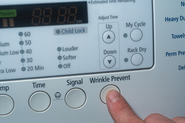 Finger pushing wrinkle prevent button on electric dryer