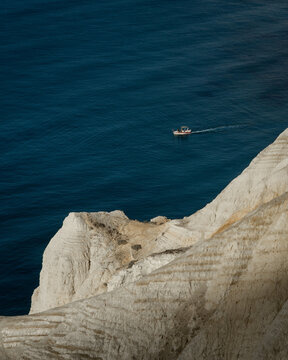 boat in blue cape Aspro with cliffs in front 