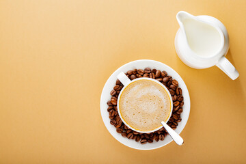 Cup of coffee on a beige background. Roasted coffee beans in a white saucer. Earth color concept....